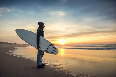 Man on beach against sky during sunset