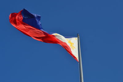 Low angle view of flag against blue sky