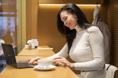 Side view of smiling businesswoman siting at cafe