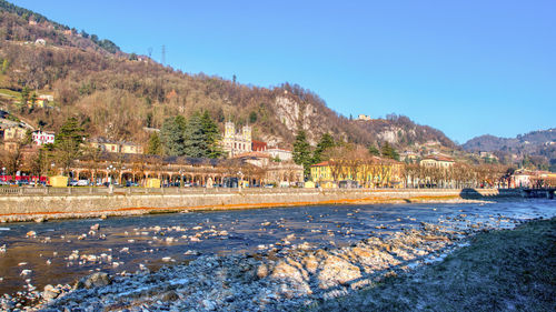 Scenic view of building by mountains against clear blue sky