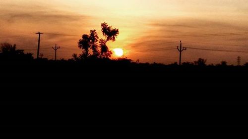 Silhouette of electricity pylon at sunset