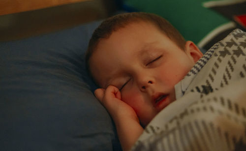 Close-up of cute baby boy lying on bed at home