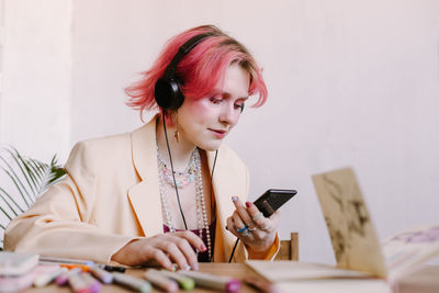 Creative young woman using smartphone , listen to music with scetchbook and painting markers