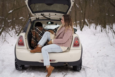 Woman sitting in car trunk
