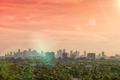 Modern buildings in city against sky at sunset