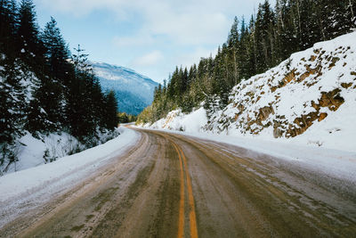 Road amidst snowcapped mountains against sky during winter