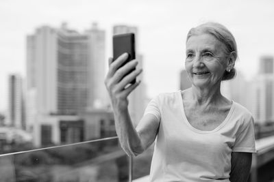 Portrait of woman photographing with mobile phone