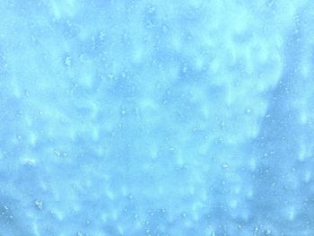 Low angle view of snowflakes on blue sky