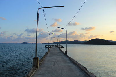 Pier over sea against sky during sunset