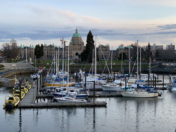 Sailboats moored on river by buildings against sky on vancouver island 