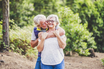 Man kissing woman against trees