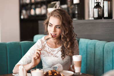 Young woman eating food at restaurant