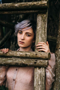Portrait of young woman holding wooden fence