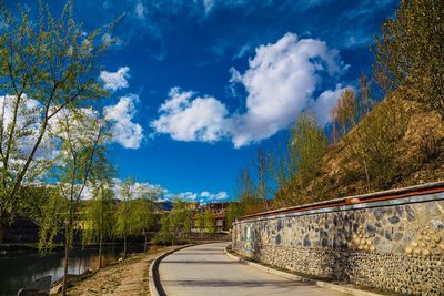 Road amidst trees against blue sky