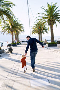 Man and woman walking on palm tree in city