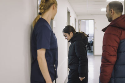 Side view of female patient entering in consulting room with father at hospital