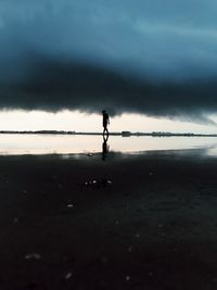 Silhouette man standing on beach against sky