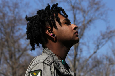 Portrait of young man looking away against sky