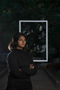 Portrait of woman standing against tree