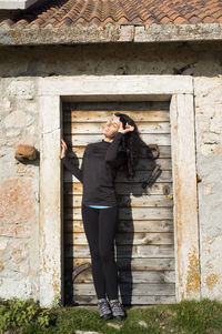 Rear view of man standing against old house