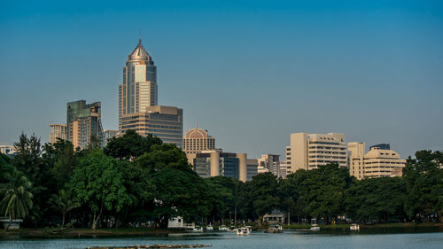 Lake by buildings against clear sky