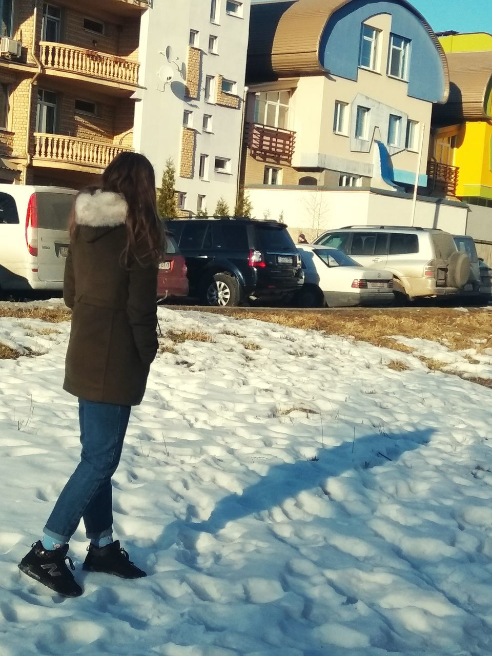 building exterior, architecture, built structure, city, winter, car, mode of transportation, transportation, cold temperature, motor vehicle, snow, street, land vehicle, one person, standing, full length, building, real people, lifestyles, outdoors, warm clothing