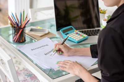 Midsection of businesswoman working at desk in office