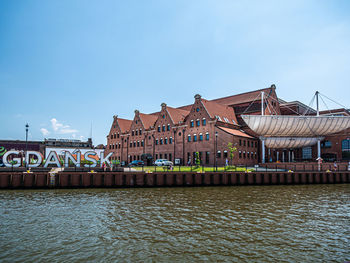 View of buildings by river against sky