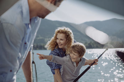 Boy with parents on a sailing trip pointing his finger