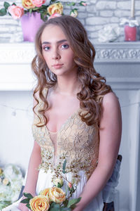 Portrait of beautiful young woman standing against white wall