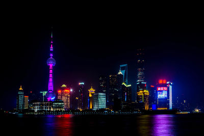 Illuminated cityscape by huangpu river against sky at night