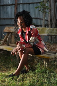 Portrait of smiling young woman sitting on bench