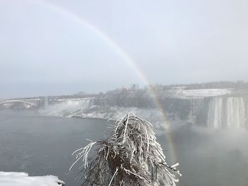 Scenic view of rainbow over water against sky