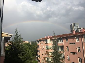 Rainbow over buildings in city against sky