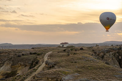 Hot air balloons flying over landscape against sky during sunset