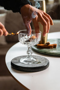 Close up of female hand burning cinnamon stick over drinking glass