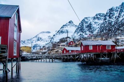 Bridge over lake in town against snowcapped mountains