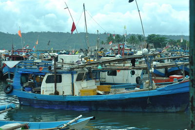 Boats moored at harbor against sky