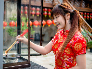 Side view of a smiling girl holding red outdoors