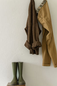 Close-up of clothes hanging over rubber boots against wall