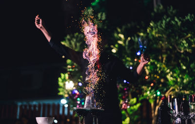 Midsection of person with illuminated lights at night