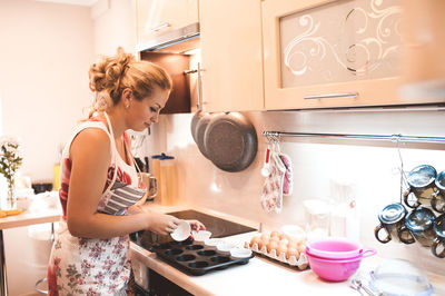 Happy woman with baking tray standing by kitchen counter