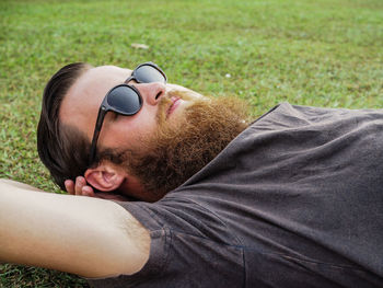 Close-up of bearded young man relaxing on grassy field