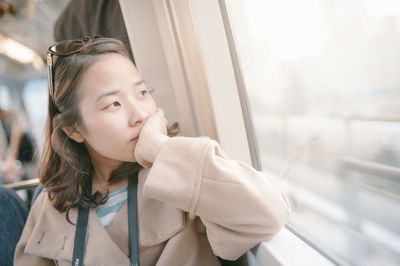 Thoughtful woman looking towards window in train