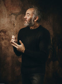 Side view of man holding trophy against black background