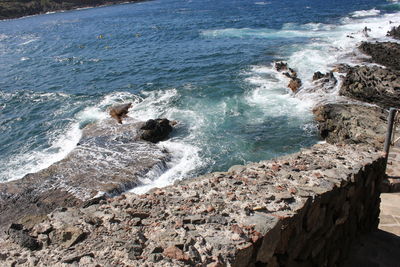 High angle view of sea waves splashing on rocks