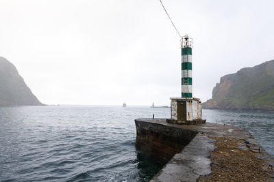 Lighthouse by sea against sky