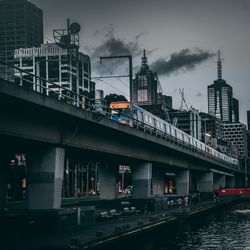 Train on bridge over river in city against sky