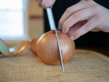 Midsection of person holding pumpkin on cutting board