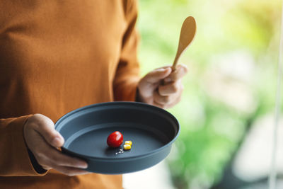 Closeup image of a woman holding a plate of small amount of food for diet concept